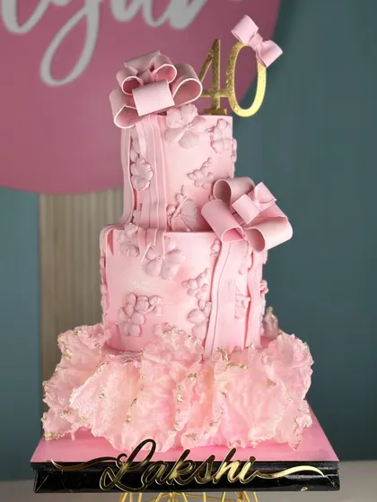 Pretty in pink and blooming with charm. This dreamy cake for a 40th birthday is adorned with delicate bows, floral textures, and a soft pink hue for a picture-perfect celebration.