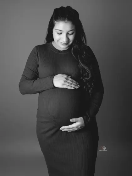 A simple, elegant black and white portrait of a mom-to-be lovingly looking down at her bump. This is a classic and heartfelt pose that never goes out of style.