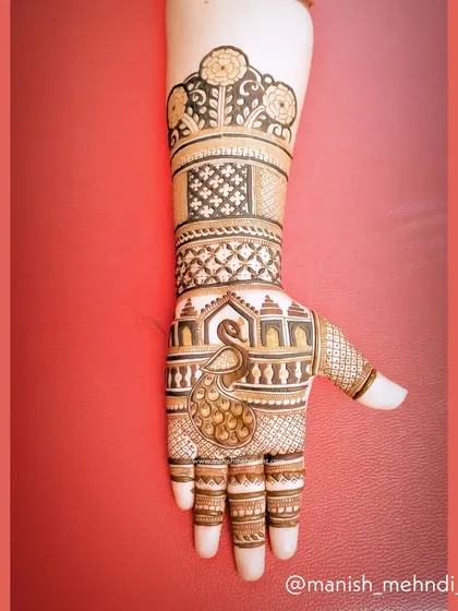 This design features a peacock on the palm, with its feathers flowing up the arm. The intricate details in the peacock and the surrounding patterns showcase a high level of artistry.