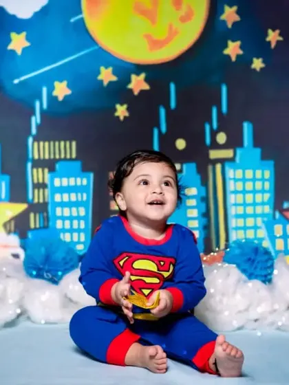 Little Aadvik is ready to save the day in his Superman costume. My superhero theme comes with a city skyline backdrop for an action-packed first birthday shoot.