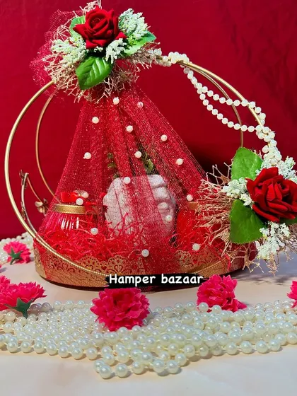 A stunning red-themed hamper in a metal ring basket, perfect for Diwali or Karwachauth. The intricate wrapping and floral details make it a truly eye-catching gift.