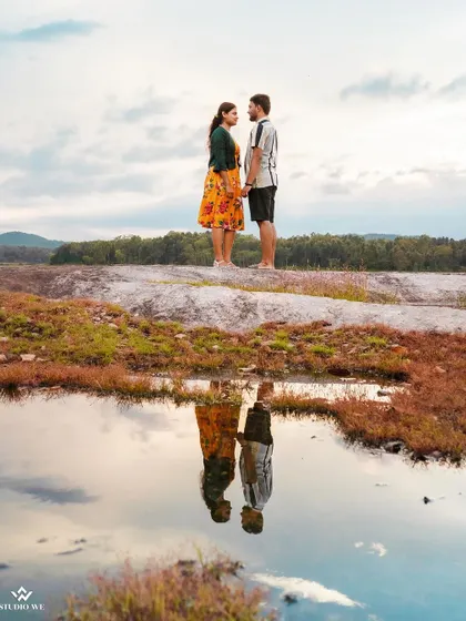 A creative reflection shot of a couple standing on a rock. The perfectly still water creates a mirror image, resulting in a stunning and artistic photograph.