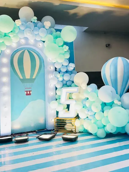 A dreamy hot air balloon theme in shades of blue and white, with a light-up archway and marquee number.