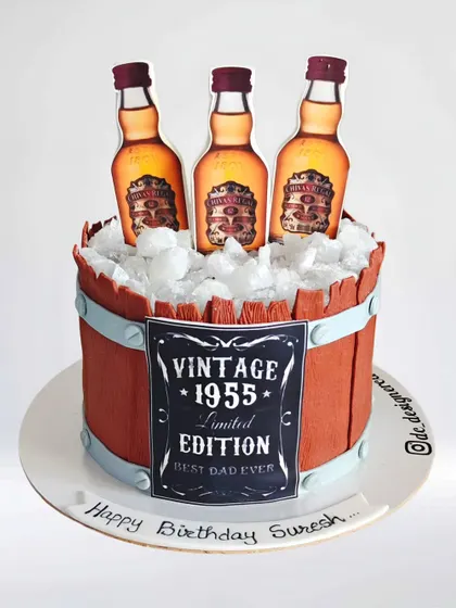 A Chivas Regal-themed barrel cake for a 70th birthday. This "Vintage 1955" cake is designed to look like a wooden barrel filled with ice and whiskey bottles.
