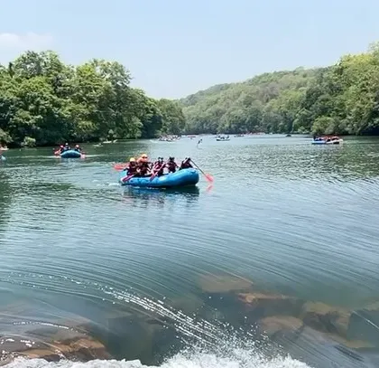 A wide view of the Kali River with multiple rafts and kayaks, illustrating the scale of our summer camp activities in Dandeli.
