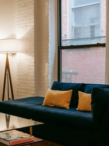 A modern living room with a deep blue velvet sofa and a glass coffee table, perfect for a contemporary apartment. The design is clean, stylish, and functional.