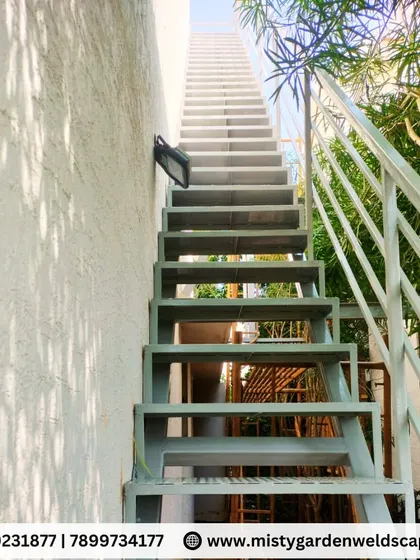 A full view of the outdoor metal staircase, showing how it provides practical access to an upper level. The grey powder-coated finish ensures it is protected from the elements and will last for years.