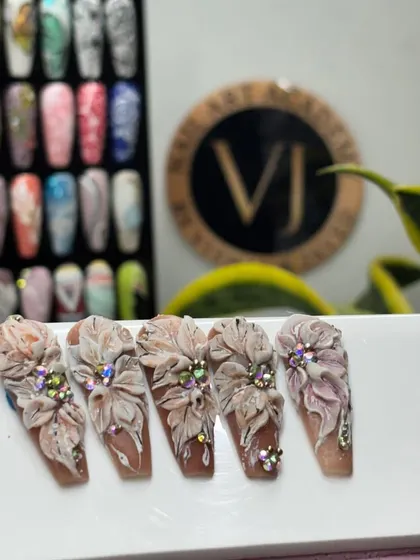 A showcase of our intricate 3D floral nail art. These long, coffin-shaped nails feature sculpted flowers embellished with sparkling rhinestones, demonstrating our advanced design capabilities.
