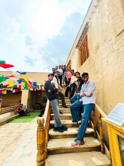 A group photo at a monastery, showcasing the unique architecture and the vibrant prayer flags that are a constant, beautiful presence throughout Spiti.