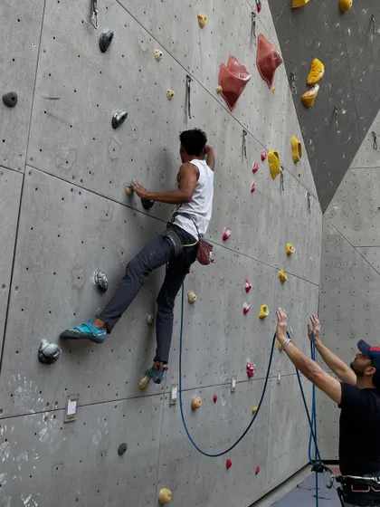 A belayer carefully manages the rope for his partner, ready to catch a fall. Our workshops emphasize the importance of attentive and safe belaying.