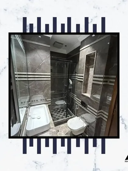 A full view of a modern bathroom with a glass-enclosed shower, wall-mounted WC, and a sleek vanity. The combination of different tiles adds texture and interest.