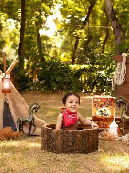 This little guy is having a blast, popping out of a log barrel during his outdoor cowboy-themed photoshoot.