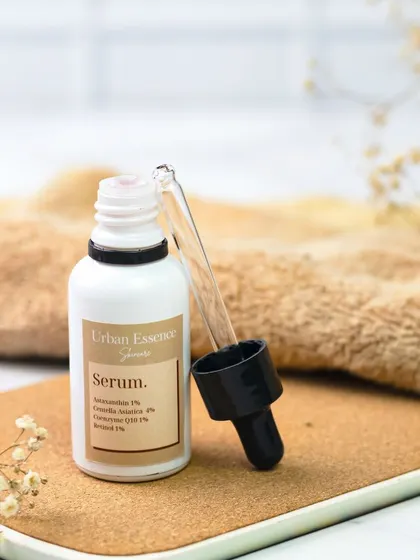 This simple, earthy composition features a serum bottle on a cork surface with delicate dried flowers. The natural textures and warm tones create a feeling of gentle, organic skincare.
