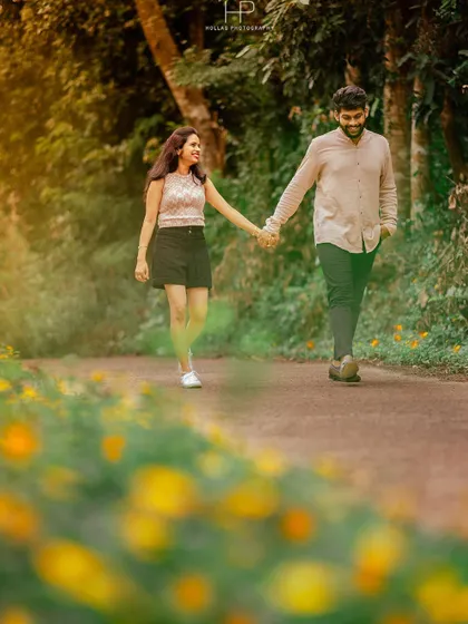 A candid shot of a couple walking hand-in-hand down a path lined with yellow flowers. This casual and romantic image is perfect for a post-wedding or pre-wedding storytelling shoot.