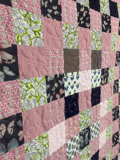 A close-up of the butterfly-themed memory quilt, showing the different textures and the professional longarm quilting.