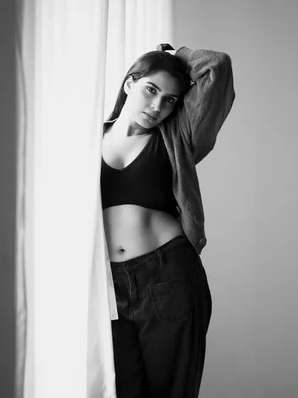 A thoughtful pose by the window. The black and white processing brings out the subtle details in the lighting and the subject's expression.