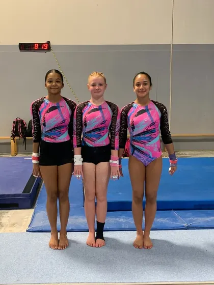 Three members of our Xcel Gold team standing proud after competing at the sectional qualifier in Spring, Texas.