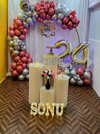 A 24th birthday party setup in our Kanakapura party hall, featuring a rose gold and silver balloon arch and light-up letters.