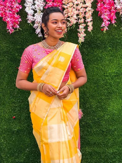 A lovely yellow and pink combination, this blouse features delicate embroidery that elevates the simple cotton saree.