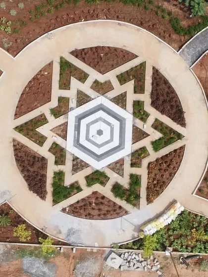 An aerial photo of a geometric garden at 'The Sanctuary' during construction, showing the pattern being laid out with soil and starter plants, next to its vibrant final render (178).