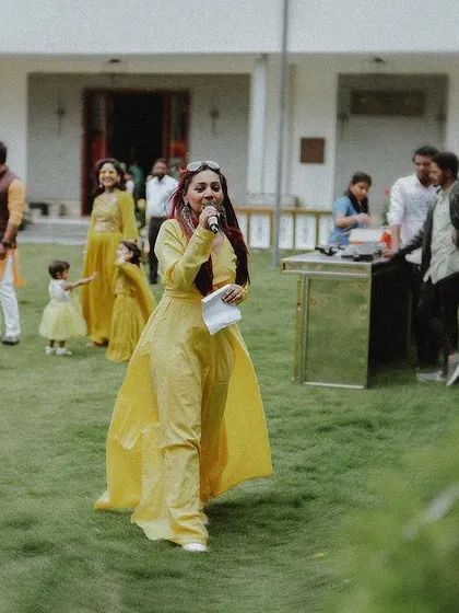 The bride, acting as the emcee, walks across the lawn during the Haldi event.