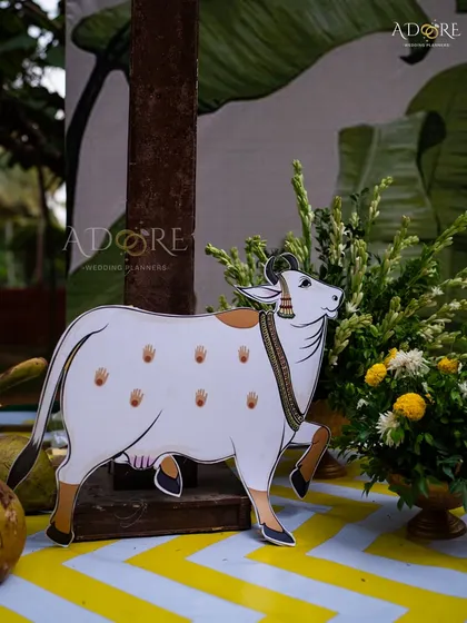 Another detail from the 'Banana Grove' theme, showing the hand-painted cow prop next to a floral arrangement, which adds a touch of authenticity and tradition to the wedding decor.