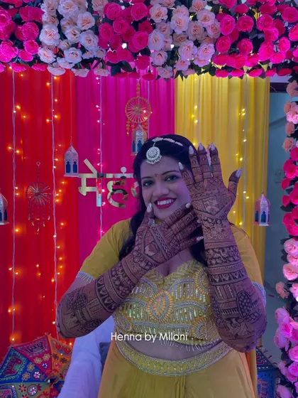 A happy bridesmaid showing off her full-hand mehendi at the ceremony.