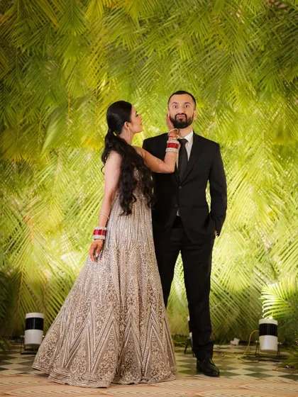 A playful, candid shot of the bride and groom against a vibrant green backdrop, showcasing their fun-loving personalities.