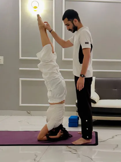 Assisting a client with a supported headstand (Sirsasana). I ensure her alignment is perfect to build core strength and confidence in inversions.