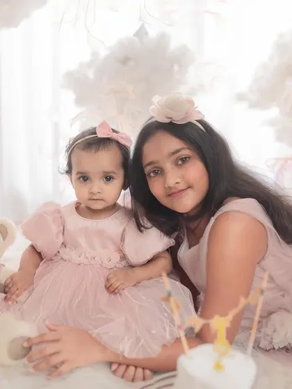 A lovely portrait of two sisters at a first birthday party. The coordinated pink outfits and dreamy setup make this a picture-perfect memory.