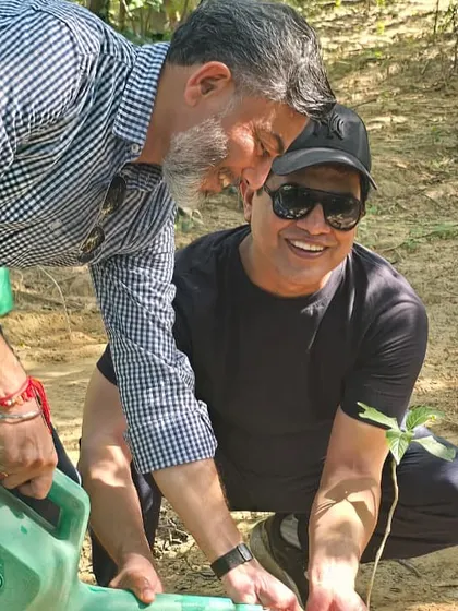 A heartwarming moment between two volunteers as they water a young sapling, a testament to the community spirit fostered during our plantation drives.