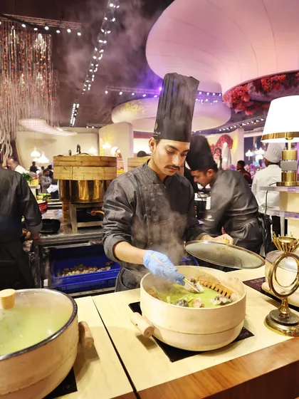 A chef at our live dim sum station, carefully arranging steamed dumplings. The traditional bamboo steamers and focused preparation add an element of authenticity and theatre to the dining experience.