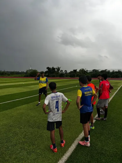 A group of our residential players listen intently to a coach's instructions on the pitch. The dramatic sky and expansive field highlight the inspiring setting where our athletes train.