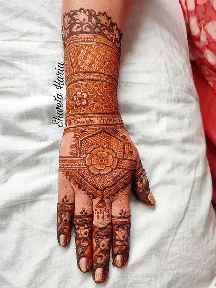 A classic back-hand design with 'Shubh Vivah' (Happy Wedding) written on the wrist. This style, featuring a central floral hexagon and patterned bands, is a timeless choice for wedding guests.
