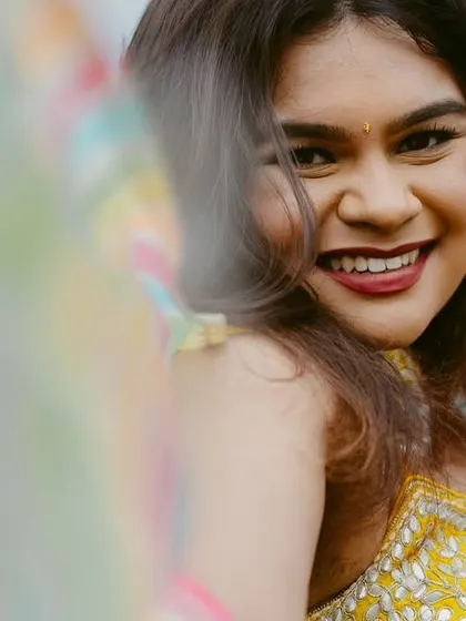A candid, happy portrait of a bride, her smile captured through a colorful, blurry foreground.