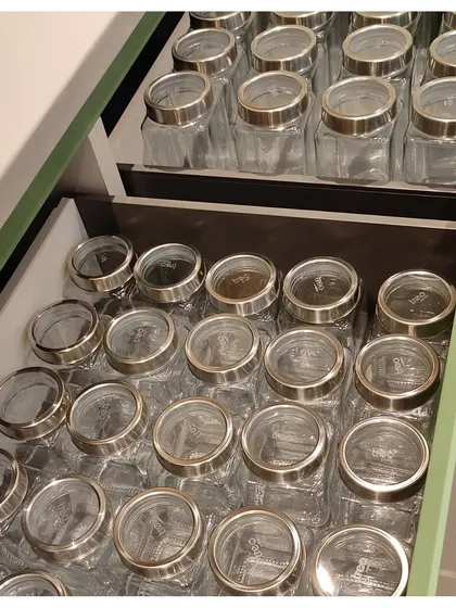 These tiered drawers are filled with uniform glass jars for spices. This setup makes it incredibly easy to find the exact spice you need without having to dig through a cluttered cabinet.