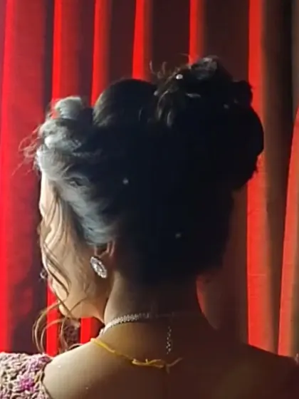 A voluminous, high-fashion updo with intricate twists and pearl accents, perfect for a grand reception look.