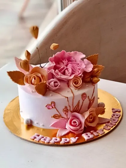 I believe every celebration deserves a beautiful cake. This custom birthday cake features intricate, handcrafted sugar flowers in shades of pink and gold, showcasing the detailed artistry I bring to every personalized order.