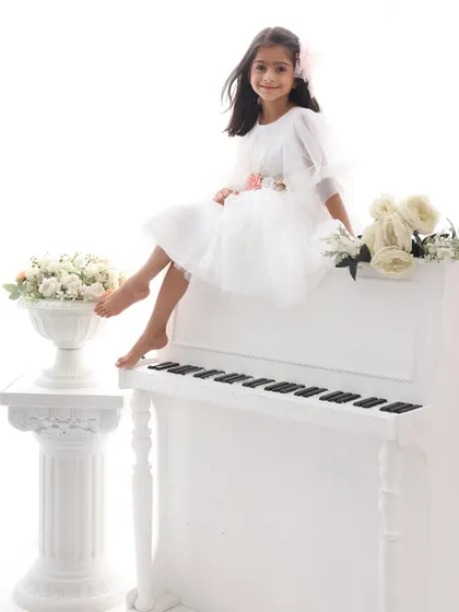 The main character in her own story. This shot of the little girl sitting elegantly atop the white piano is full of charm, confidence, and whimsy.