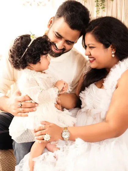 A close-up, intimate family portrait showing the loving gaze between parents and their child.