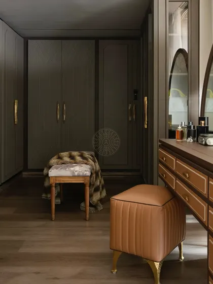 This classic walk-in closet features dark wood wardrobes with diamond-patterned details and elegant brass handles. A leather-upholstered vanity stool adds a touch of warmth and luxury.