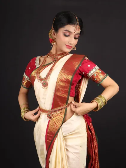 An elegant Murtham bride in a classic white and red silk saree. The makeup is kept soft and natural to complement the traditional and graceful aesthetic.