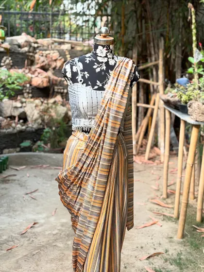 The combination of the modern blouse and the traditionally inspired striped saree creates a unique fusion look.