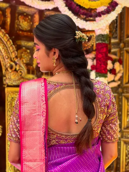 A view of the back of a client's blouse, showing a beautiful cut-out design and intricate embroidery that complements her hairstyle.