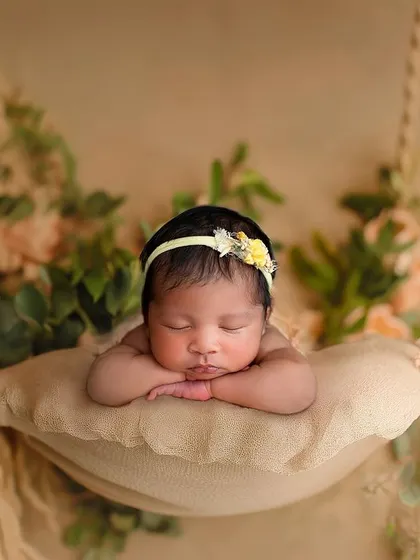 This is a composite image, combining a safe, simple shot of the baby with a beautiful digital backdrop of a hanging floral swing. The result is pure magic and completely safe for the baby.
