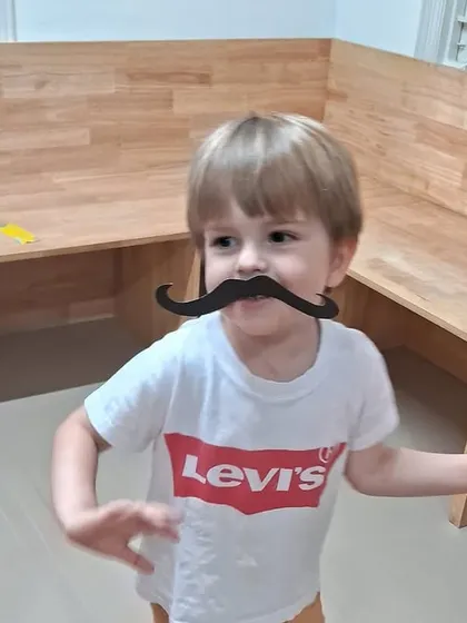 Another child having fun with a mustache prop and a red fan during our Tomatina festival.