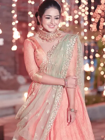 A model in a peach lehenga paired with a Kundan choker set, perfect for a daytime wedding or engagement party.