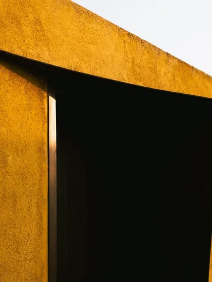 An abstract detail of the architecture, where a sharp incision in the wall creates a dramatic, dark doorway.
