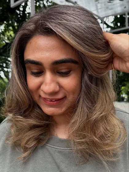 The happy client, glowing with her new blonde hair. It's a perfect match for her.