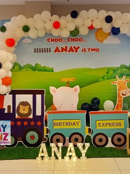 All aboard the birthday express for Anay's second birthday. This train theme setup features a custom backdrop with a "Choo Choo" design, a train cutout with animal passengers, railroad crossing signs, and light-up letters for the birthday boy's name.